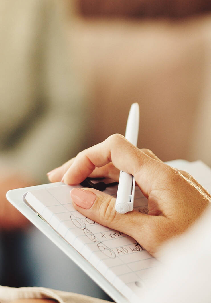 An open notebook, a gold pen and a cup of coffee on a knitted throw